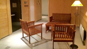 Un intérieur en bois avec deux chaises et une table en bois, une lampe et une porte donnant sur une autre pièce.