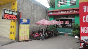 A hotel with a signboard, a motorcycle parked in front, and a red umbrella. - Thanh Dat Hotel (Ninh Binh)