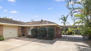 A single-story house with a garage, a covered patio, and a well-maintained lawn.