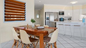 A modern kitchen with white cabinets, stainless steel appliances, and a bar area with stools. - Relaxation & Space in a Canal Home (BANKSIA BEACH)
