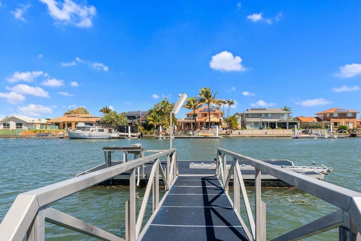 A marina with a dock leading to a building with a sloped roof and solar panels.