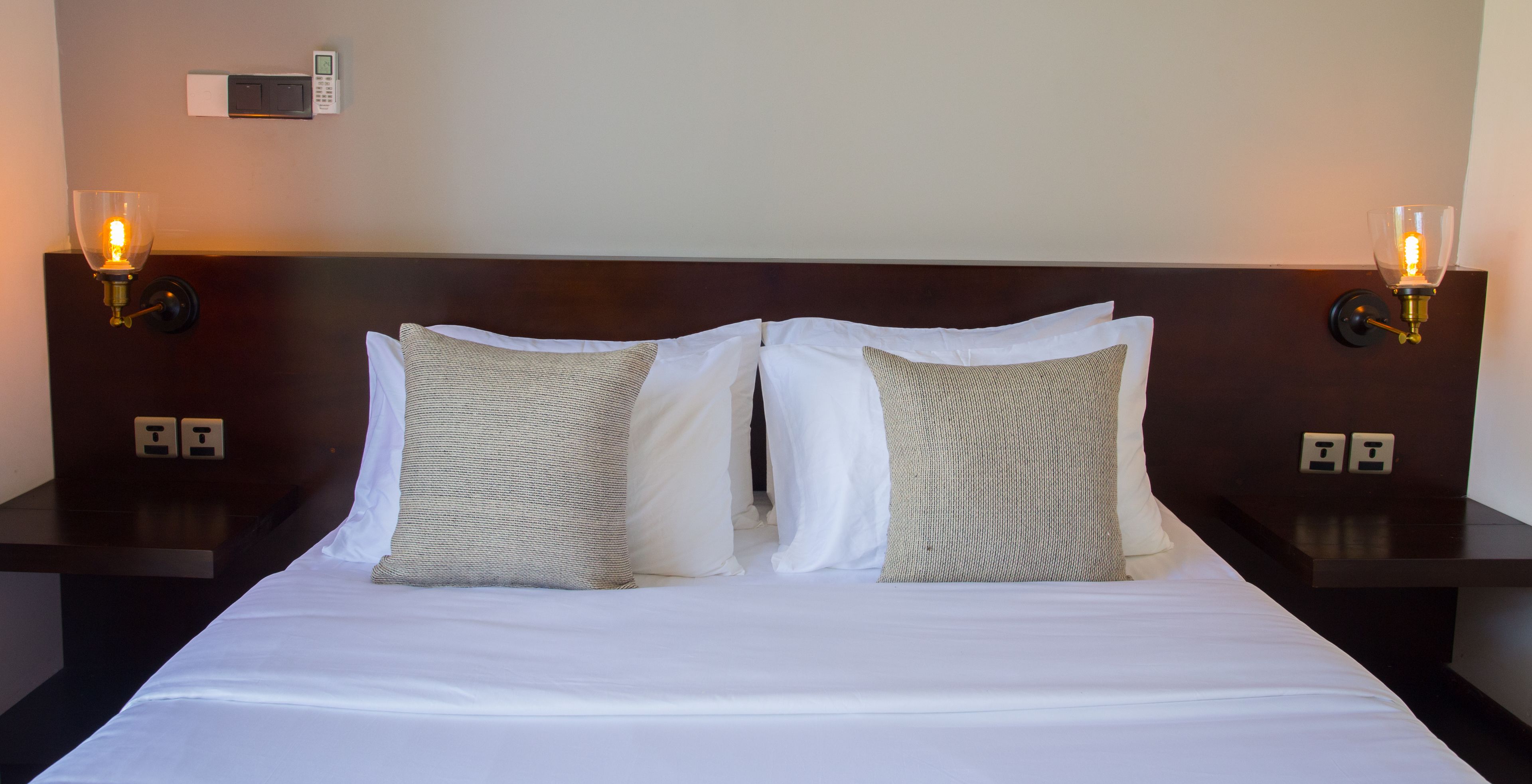 A hotel room with a large bed, two bedside tables, and two wall-mounted lamps.