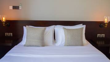 A hotel room with a large bed, two bedside tables, and two wall-mounted lamps.