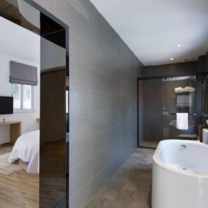 Une salle de bain moderne dotée d’une grande baignoire, d’un espace douche et d’un meuble-lavabo avec un miroir.
