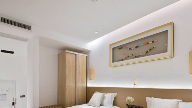 A hotel room with two beds, a wooden wardrobe, a framed artwork on the wall, and a small table with a flower. - Floral Hotel Gulangyu Haiyun Garden (Xiamen)