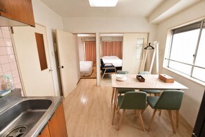 A compact hotel room with a kitchenette, a dining area with a table and chairs, a bed, and a window. - Randor Residence Tokyo Grand (Tokyo)