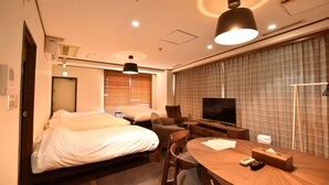 A hotel room with two beds, a desk, a chair, a television, and a window with blinds.