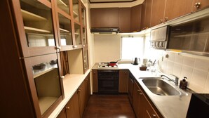 A compact kitchen with wooden cabinets, a stainless steel sink, and a built-in oven.