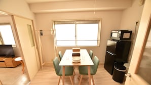 A compact kitchen with a dining table, chairs, a microwave, and a refrigerator.