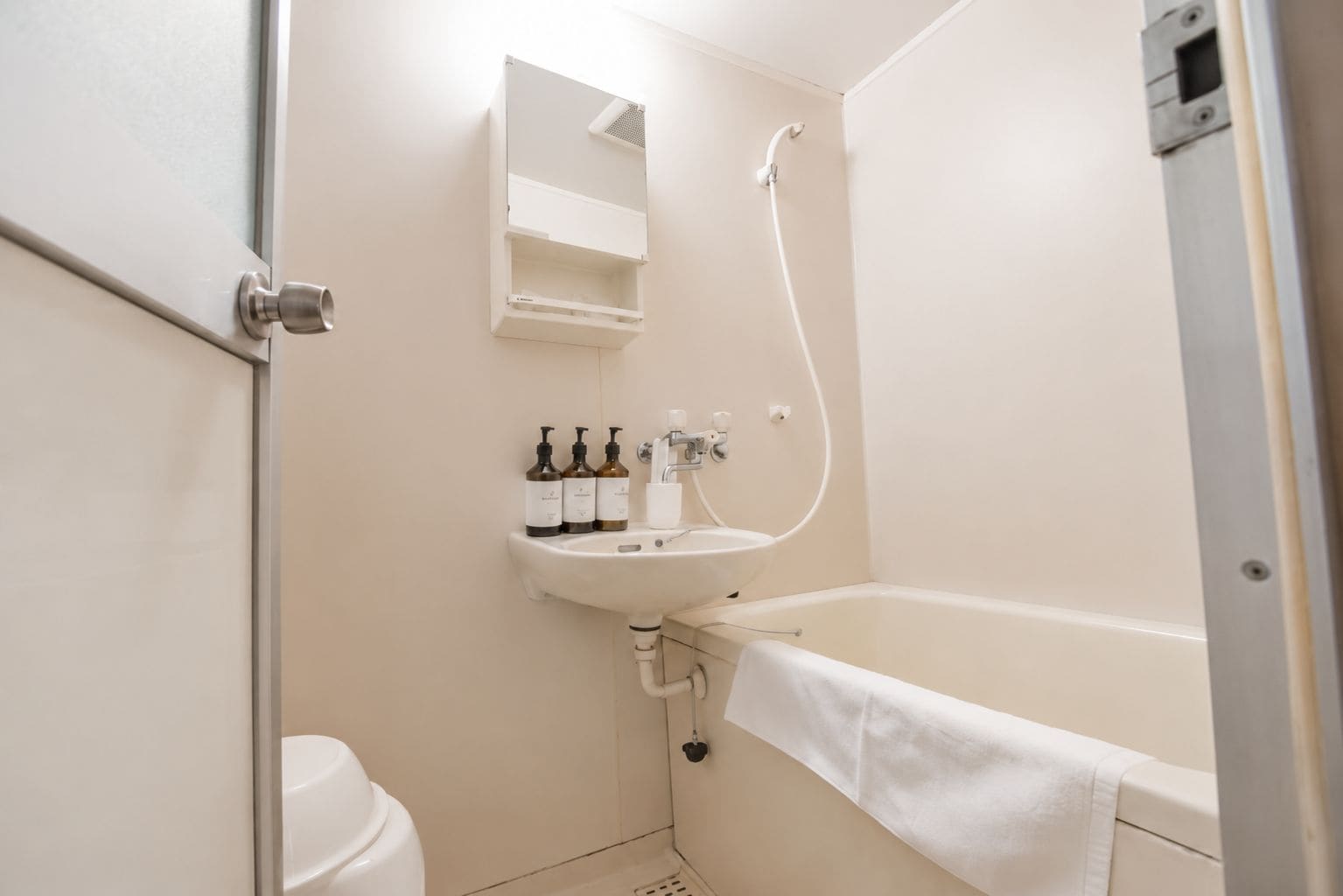 A bathroom with a white sink, a mirror, a shower, and a toilet.