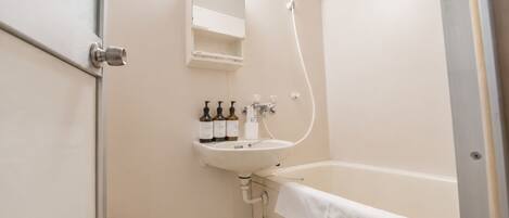 A bathroom with a white sink, a mirror, a shower, and a toilet.