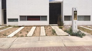 A modern building with a flat facade, large windows, and a central door. - Hermosa casa completa en coto privado (Aguascalientes)