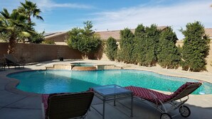Piscina com mesa de vidro e duas espreguiçadeiras.