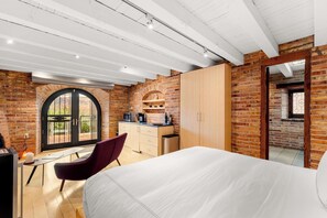 Une chambre comprenant un lit, un bureau, une chaise, une armoire et un coin cuisine équipé d’un four à micro-ondes.