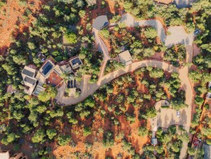An aerial view of a residential area with winding roads, solar panels on buildings, and dense greenery. - Eagle Dancer Guest Suite | Wellness Spa & Trails (Sedona)