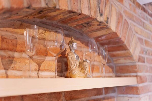 A Buddha statue on a shelf with wine glasses.