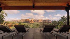 A covered outdoor area with lounge chairs, a wooden ceiling, and a view of a mountainous landscape.