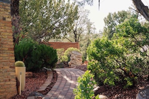 A landscaped garden with a curved brick pathway, a cactus, and various shrubs. - Eagle Dancer Guest Suite | Wellness Spa & Trails (Sedona)