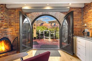 A room with a fireplace, a dining area, and a view of a mountainous landscape through a glass door.