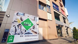 A hotel facade with a large advertisement for a hotel chain, multiple windows, and a clear sky. - CHECKinn Express New Taipei Tamsui (New Taipei City)