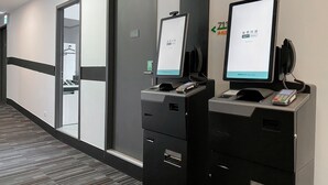 A hotel reception area with a digital check-in kiosk, a telephone, and a small screen displaying a welcome message. - CHECKinn Express New Taipei Tamsui (New Taipei City)