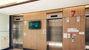 An elevator with wooden paneling and digital displays indicating floor 7. - CHECKinn Express New Taipei Tamsui (New Taipei City)