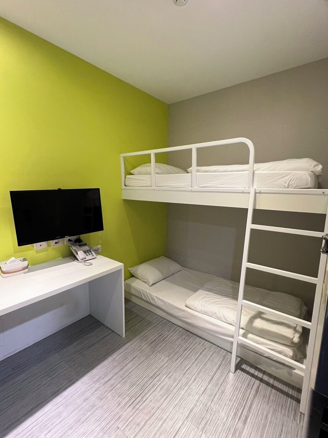 Une chambre avec un lit superposé, un bureau et un téléviseur.