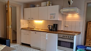 A compact kitchen with white cabinets, a built-in oven, and a coffee maker.