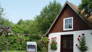 A traditional wooden house with a sloped roof, a white exterior, and a dark brown door.