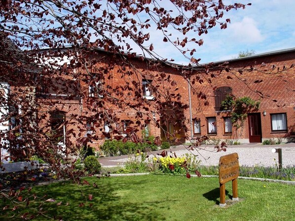 Un bâtiment en briques avec un jardin devant.