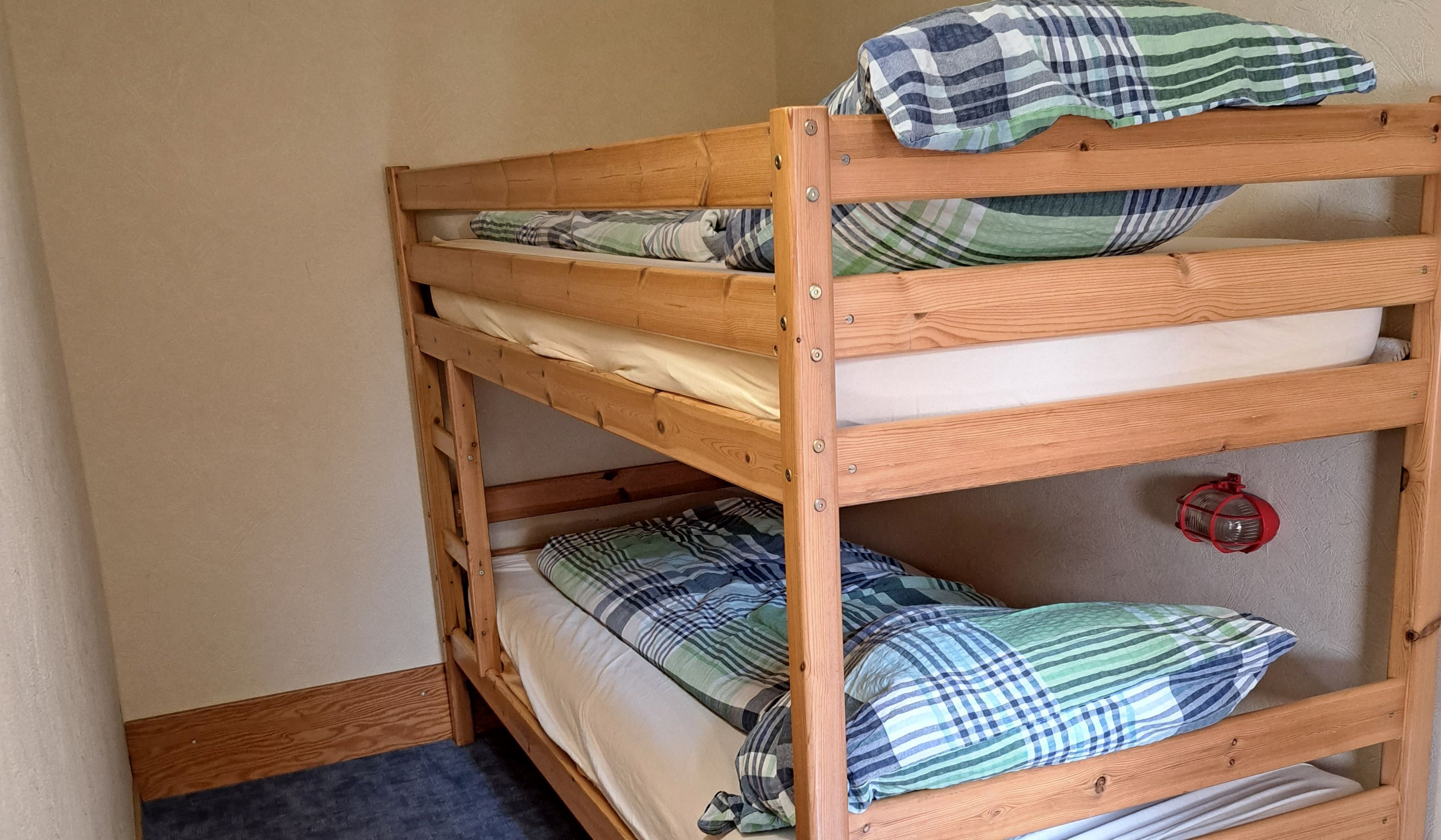 Una cama litera con dos niveles, cada uno con almohada y manta.