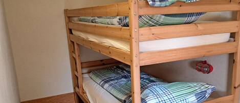A bunk bed with two levels, each with a pillow and a blanket.