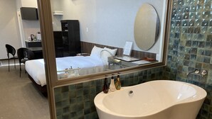 Une salle de bain moderne avec une baignoire sur pieds, un grand miroir et un mur recouvert de carreaux.