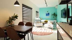 Une cuisine moderne dotée d’un îlot central, un coin repas avec une table et des chaises en bois, et un espace de vie comprenant un canapé et une table basse.