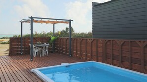 Une terrasse en bois avec une piscine, un espace salon extérieur et une pergola.