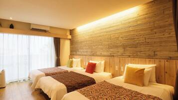 Habitación de hotel con dos camas, cabecero de madera, ventanas amplias con cortinas y un equipo de aire acondicionado visible.