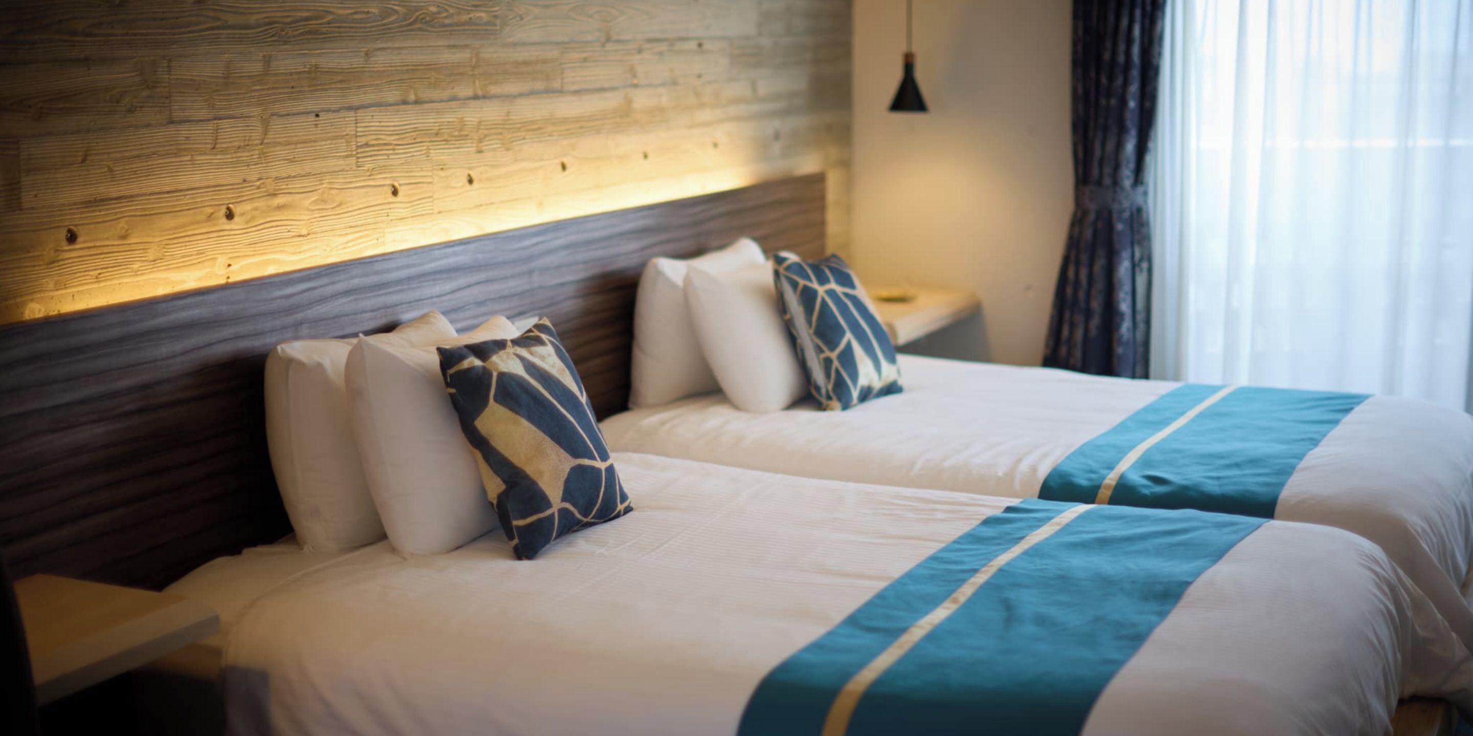 A double bed with a wooden headboard, two pillows, and a blue and white striped bedspread.