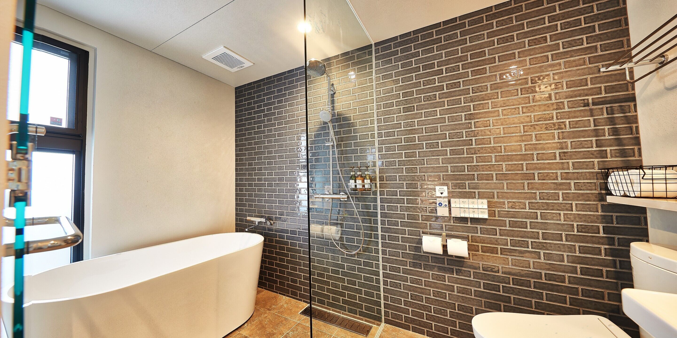 Ein modernes Badezimmer mit einer gläsernen Dusche, einer freistehenden Badewanne und einem WC.