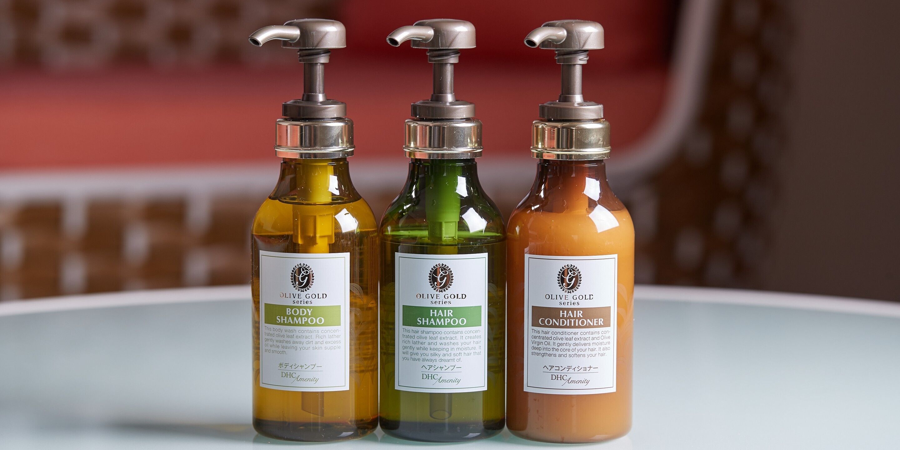 Tres botellas de productos capilares de la línea Olive Gold sobre una superficie blanca.