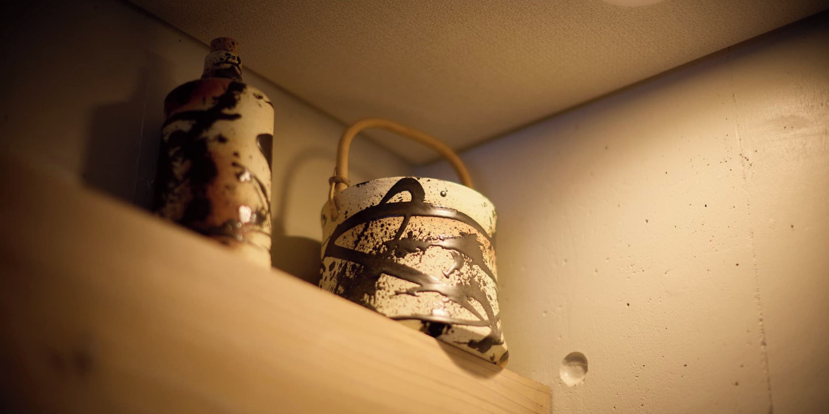 Uma prateleira com dois objetos decorativos, um com puxador e outro cilíndrico.