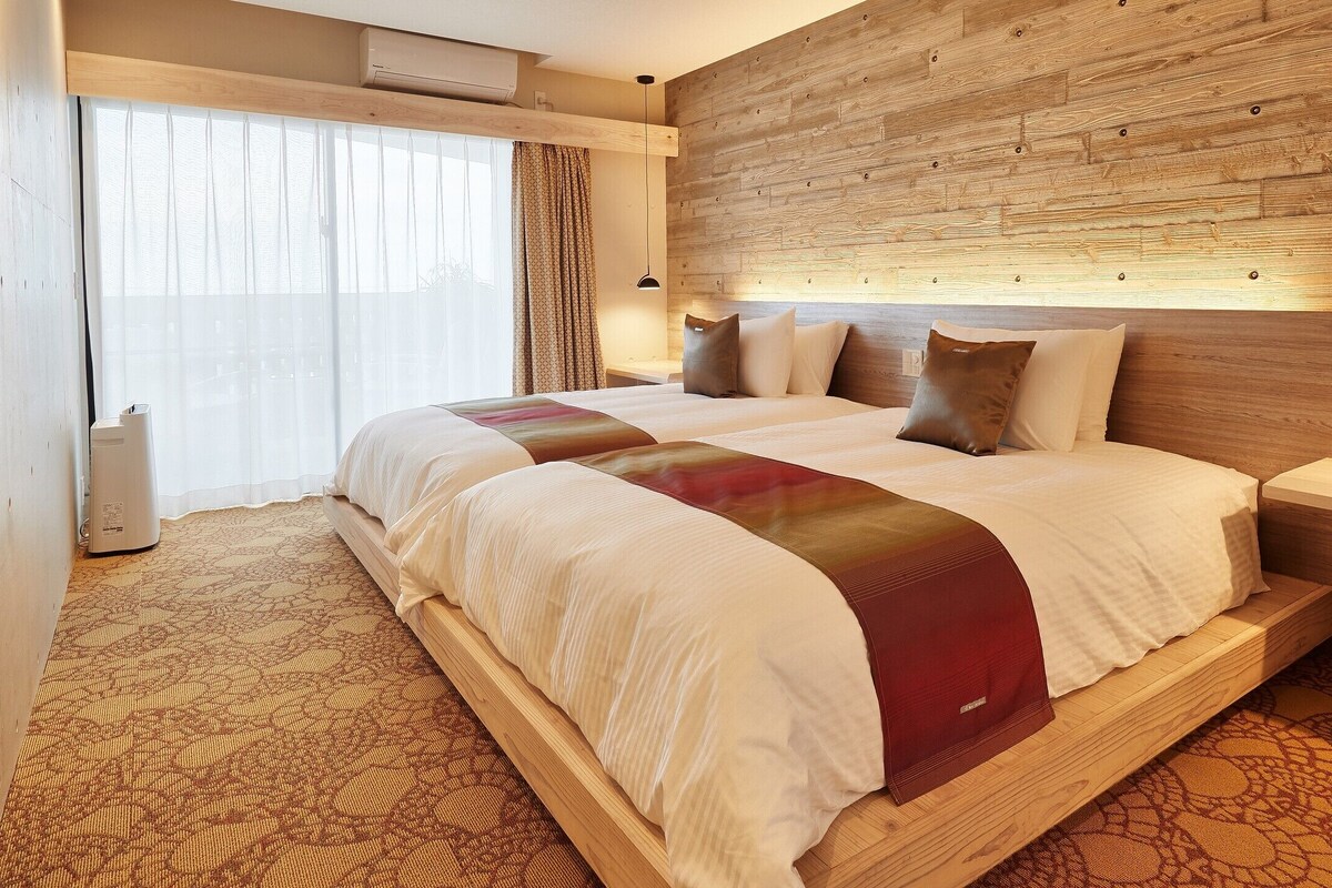 A hotel room with a large bed, wooden headboard, and a patterned carpet.