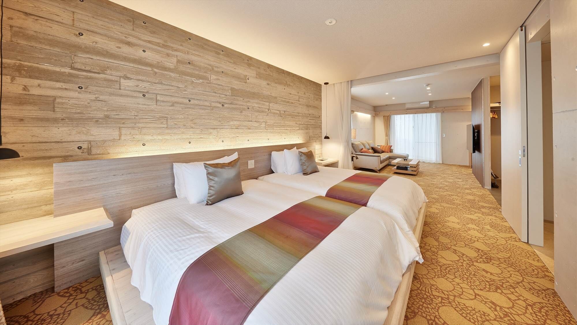 A hotel room with a large bed, a wooden headboard, a bedside table, a TV, and a bathroom visible through an open door.