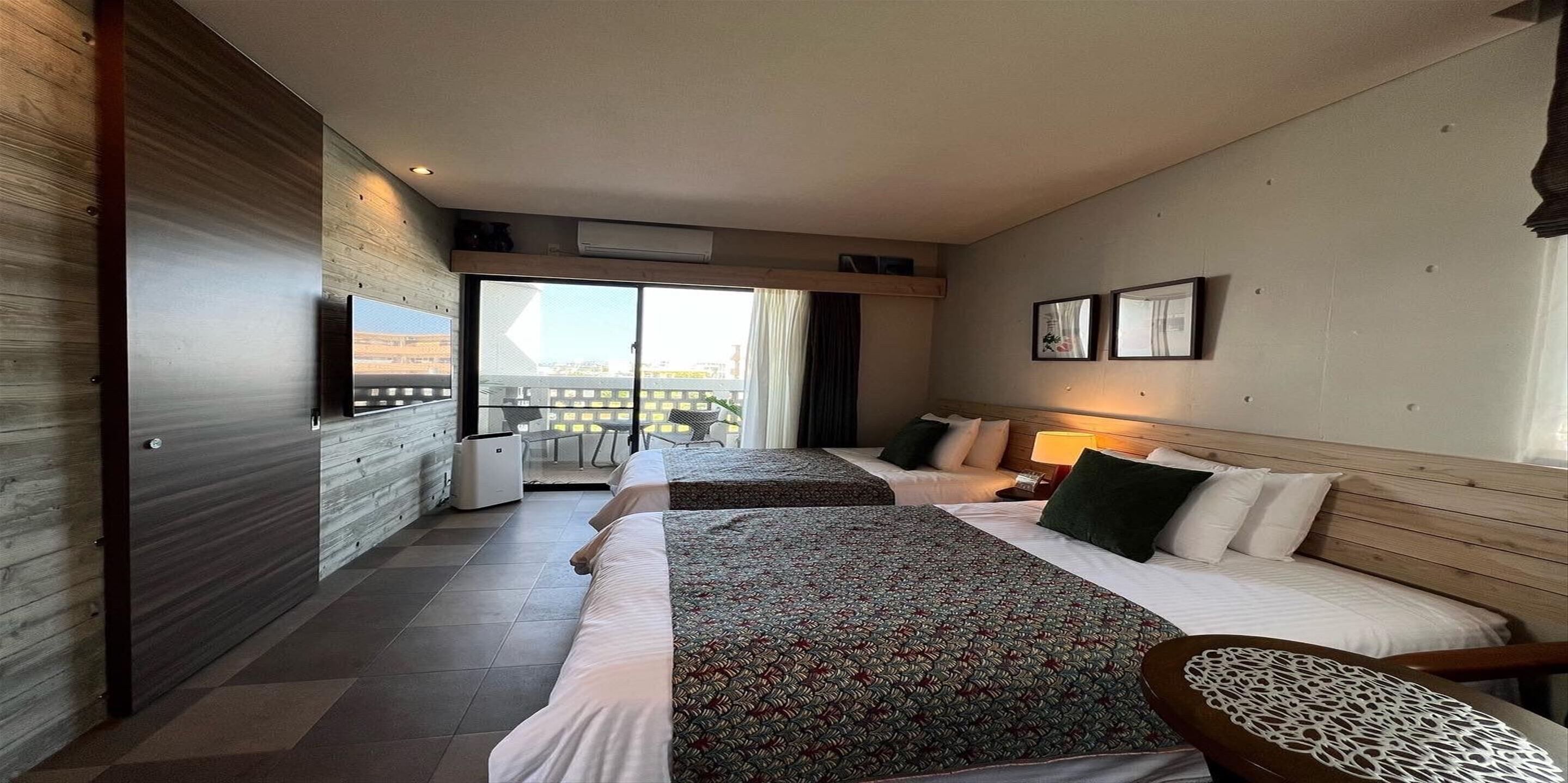 Habitación de hotel con dos camas, un balcón y vistas a la ciudad.