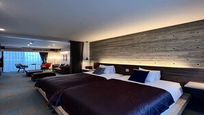 A modern hotel room with a large bed, a desk, and a seating area with chairs. - Yomitan Condhotel ND (Yomitan)