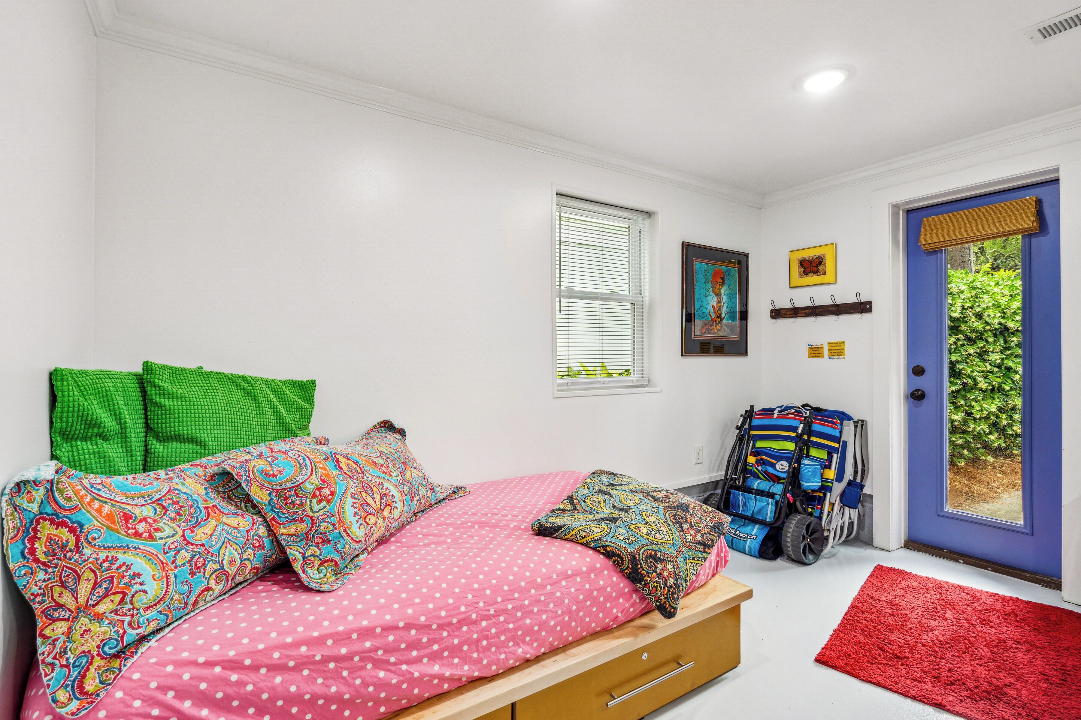 Un dormitorio con cama, ventana, puerta y una alfombra roja.