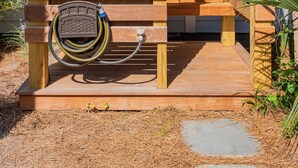 A wooden structure with a hose connected to a metal object, possibly a water feature, and a stone pathway leading to it.