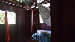 A room with wooden walls and a bed with a striped bedspread. - Casa Hospedaje Tingo Maria (Rupa-Rupa)