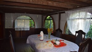 A dining area with a table set for two, featuring a white tablecloth, a vase with flowers, and a bottle of sauce. - Casa Hospedaje Tingo Maria (Rupa-Rupa)