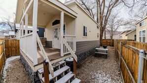 Une maison mobile de plain-pied, dotée d’un porche, d’une petite terrasse et de fondations en pierre.