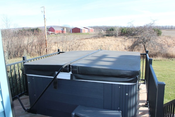 A hot tub on a deck with a view of a rural landscape.